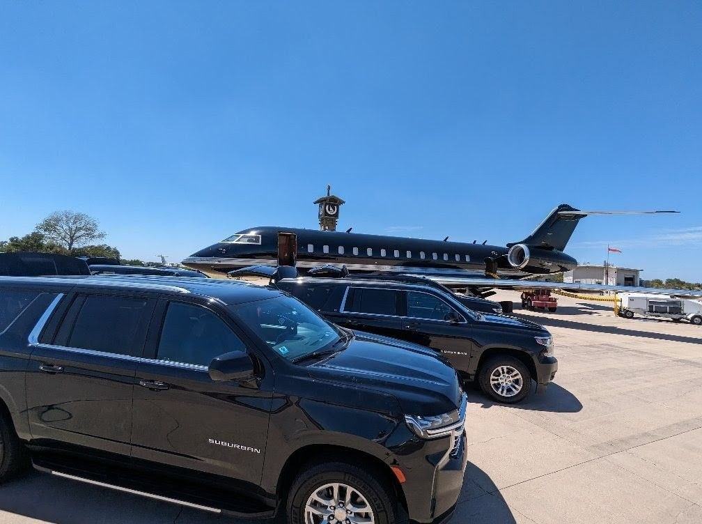 Two Ubiquitous Driver Suburbans on the tarmac beside a private jet